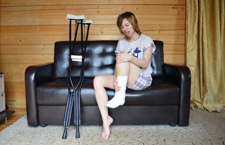 A woman who is suffering from a leg injury and two crutches next to her.